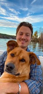 Kolton holding a dog by the water